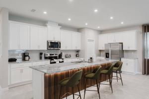 a kitchen with white cabinets and a bar with stools at Spacious 9BR Home w Private PoolGame Room in Davenport