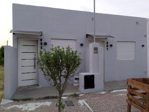 a white building with two garage doors and a tree at Departamento NAMASTE II in Carhué