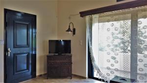 a door to a room with a tv and a window at Dionysus Blue Sky in Egina