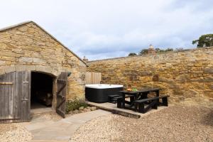 a stone wall with a bath tub and a table at Mill Cottage in Newlands