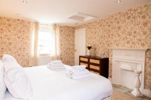 two white beds in a room with a fireplace at Mill Cottage in Newlands