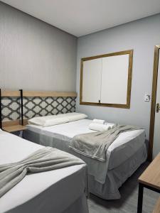 a room with two beds and a window at Hotel Dois Montes in Itamaraju