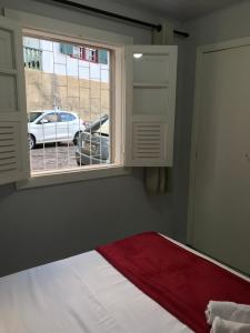 a bedroom with a window and a bed with a red blanket at Quarto Real - Centro Histórico in Diamantina