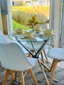 a glass table with four chairs and a table with dishes on it at BKM Lake View Retreat at Leisure Bay Estate in Pretoria