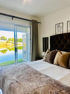 a bedroom with a large bed with a large window at BKM Lake View Retreat at Leisure Bay Estate in Pretoria