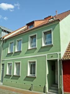 une maison verte avec des fenêtres blanches sur une rue dans l'établissement Ferienwohnung Am Ueckerpark, à Ueckermünde
