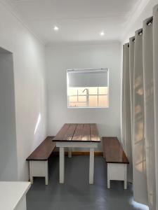 mesa y bancos en una habitación con ventana en Ougat, en Douglas