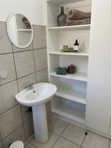 baño con lavabo, espejo y estanterías en Ougat, en Douglas