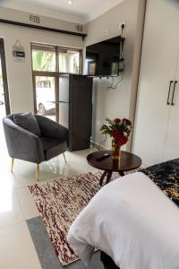 a bedroom with a bed and a chair and a table at Casa Amora! in Mpemba