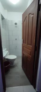 a bathroom with a toilet and a wooden door at Luvuno accommodation in Mombasa