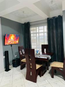 a dining room with a table and chairs and a television at Jordan House in Voi