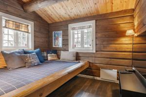 a bed in a room with wooden walls and windows at Trysilfjell 636 by Vacation Trysil in Trysil