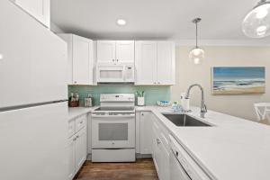 a white kitchen with white cabinets and a sink at 140 Feet To White Sandy Beaches! Newly Renovated! Pool! Grill! in Laguna Beach