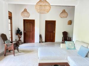 ein Wohnzimmer mit einem Sofa, Stühlen und Hängelampen in der Unterkunft Sooriya Villa in Mirissa