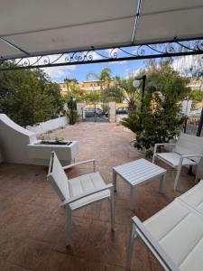 a patio with white chairs and a table at Casa delle Mimose Baia Verde in Baia Verde