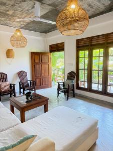 ein Wohnzimmer mit Sofa, Stühlen und Fenstern in der Unterkunft Sooriya Villa in Mirissa