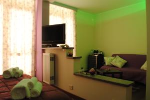 a living room with green walls and a couch and a television at Villa Regina B&B in Nettuno