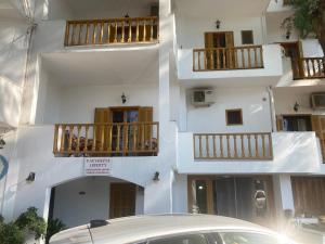 a white building with balconies and a car parked in front at Liberty-Room N2 in Georgioupolis