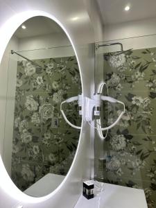 a mirror in a bathroom with floral wallpaper at Puccini Luxury Rooms in Lucca