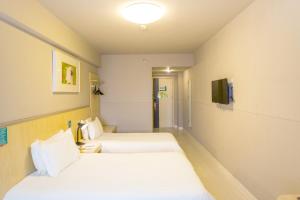 a hotel room with two beds and a tv at Jinjiang Inn Kunshan Renming Road West Street in Kunshan