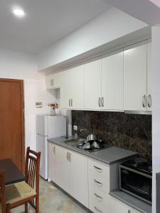 a kitchen with white cabinets and a white refrigerator at Villa Besnik in Sarandë