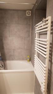 a bathroom with a tub and a white towel rack at Type 2 hypercentre 100 m de la mer in Cabourg