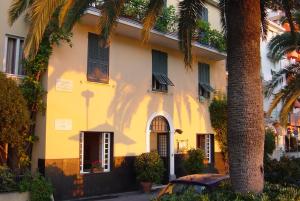 un edificio giallo con palme di fronte di Hotel Beau Rivage ad Alassio