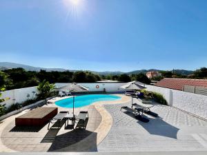 a swimming pool with chairs and umbrellas next to a building at Villa Elena - Private Villa in the heart of nature in Chania Town