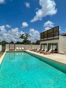 a swimming pool with chairs and a building at The Waves Tulum Secluded studio apartment with balcony in Tulum