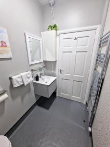 ein Badezimmer mit einer weißen Tür und einem Waschbecken in der Unterkunft Princess Red 1 - Portrush by the Sea in Portrush + 21 Fotos