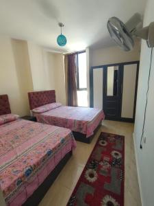 a bedroom with two beds and a rug at شالية في قرية جراند هيلز in Dawwār ‘Abd Allāh