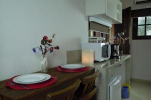 a kitchen with a table with plates and a microwave at Vila dos Caetés - Suíte 01 - Barra do Sahy in Barra do Sahy