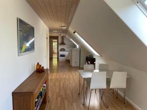 a kitchen and dining room with a table and white chairs at Stort Værelse på Landsted nær Løkken in Løkken