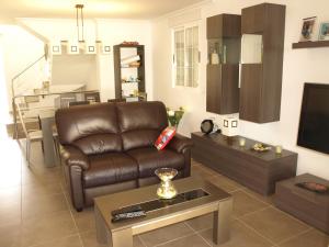 a living room with a brown leather couch and a tv at Jazmines 22 in Calpe