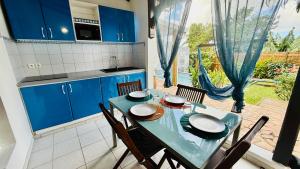 a kitchen with blue cabinets and a table with chairs at Géko, piscine, jardin, paisible in Sainte-Luce