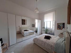 バーリにあるDimora turistica via Tanzi 27 Bariの白いベッドルーム(ベッド2台、鏡付)