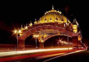 un gran edificio con un arco iluminado por la noche en Farms View, en Amritsar