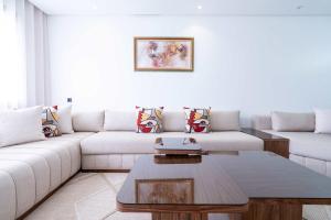 a living room with a white couch and a coffee table at Appartement avec Piscine dans Résidence Privée in Dar Bouazza