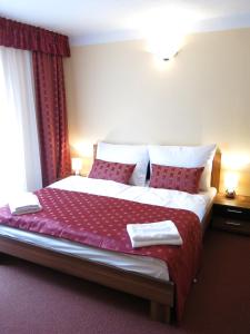 a bedroom with a large bed with red curtains at Penzion Elzet in Třeboň