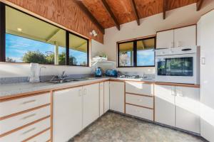 a kitchen with white cabinets and windows at Quail Rise - Collingwood Holiday Home in Collingwood +7 photos