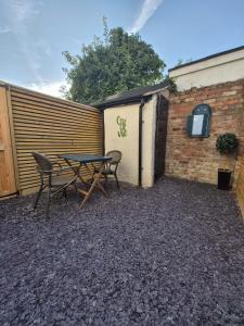 eine Terrasse mit einem Tisch und Stühlen neben einem Gebäude in der Unterkunft The Nook Cottage, Parkgate, Wirral in Parkgate