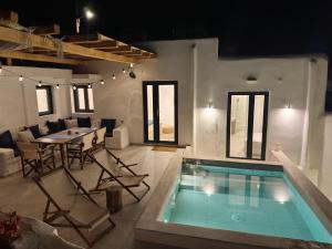 a living room with a pool and a table and chairs at Kukulú Luxurious Cottage with Mini Private Pool in Ano Mera