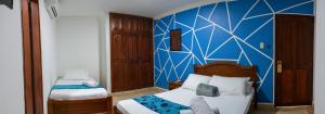 a bedroom with two beds and a blue wall at Hotel Marie Real Cartagena in Cartagena de Indias