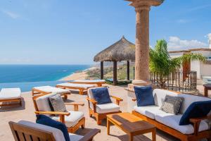 een terras met stoelen en tafels en de oceaan bij Villa Turquesa 10BR by Cabo Villas in Cabo San Lucas