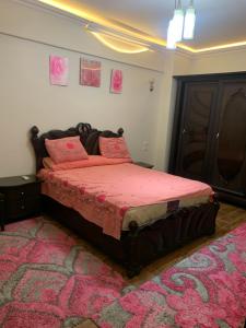 a bedroom with a bed with pink sheets and a rug at شقة للإيجار اليومي مفروشه سوبر لوكس in Manshīyat as Sādāt +11 photos