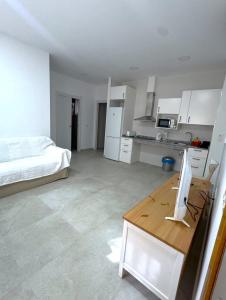 a white room with a bed and a desk with a computer at Apartamentos Maruja in Los Baños