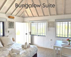 a bedroom with a bed and a table and windows at Mandala Bungalows - Adults Only in Los Caños de Meca