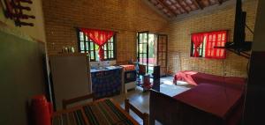 cocina con sofá y nevera en una habitación en Tahoma Chale Rustico côr Café e vermelho Prumirim Paraiso, en Ubatuba