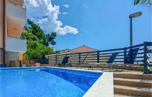 a swimming pool with chairs next to a building at Beautiful Apartment In Baska Voda in Baška Voda +10 photos