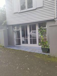 a house with a porch with a car in the window at 1 Queen Bed and 1 Sofa Bed, Serviced Studio B in Auckland